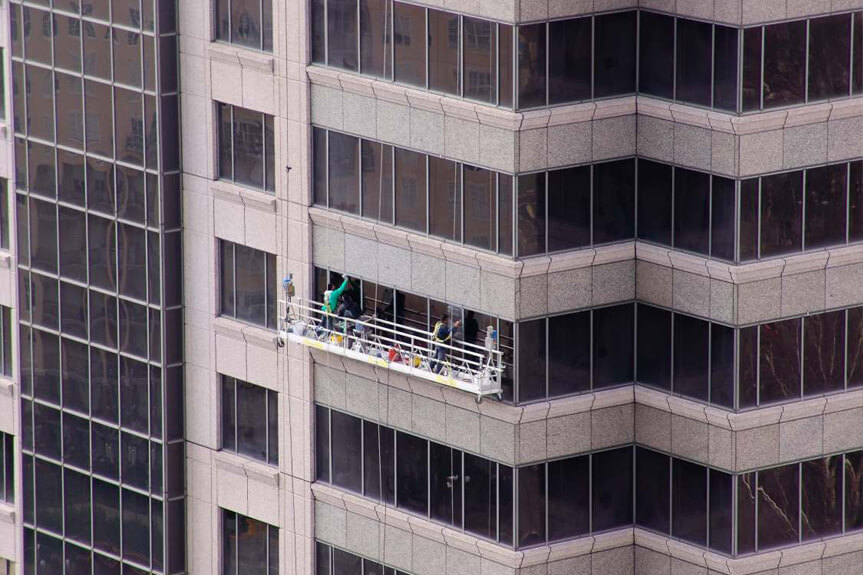 Presto technicians hang from swing stage outside high-rise office building to perform exterior glass, metal and stone restoration at 1100 Peachtree Street in Atlanta, GA