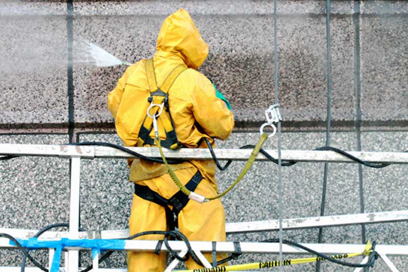 Prepping the exterior of an office building for sealing by cleaning with a sprayer